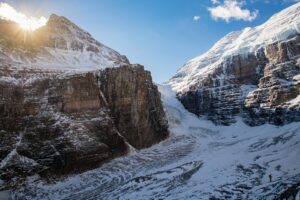 the sun shines on a snowy mountain side